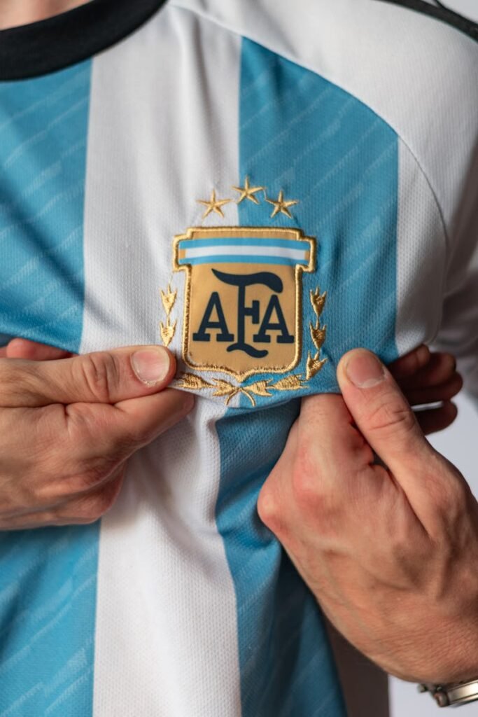 Detailed view of a person holding the emblem on an Argentina football jersey, showcasing national pride.